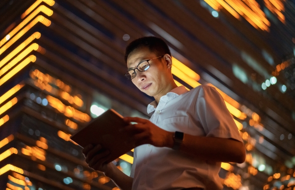 man using digital tablet outside large commercial building