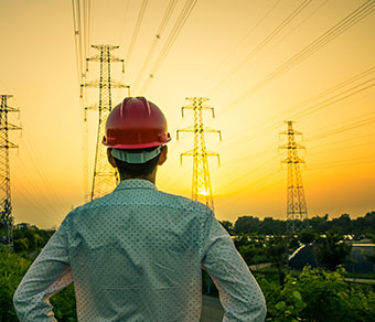 engineer looking at electrical towers at sunset