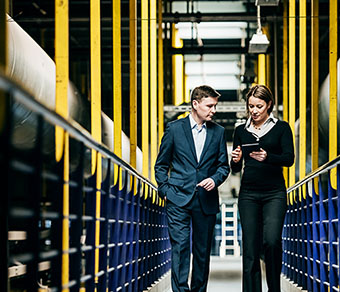 factory owner talking with operations manager while walking through plant